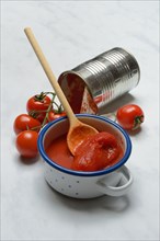 Tinned tomatoes in a bowl, tin can and tomatoes