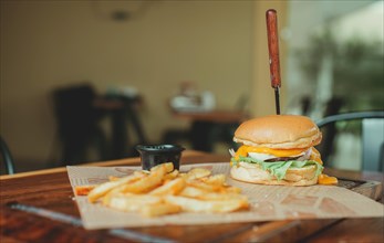 Delicious hamburger with french fries on a wooden table. Cheeseburger with french fries served on