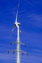 Electricity pylon with high-voltage lines and wind turbine at the Avacon substation Helmstedt,