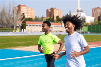 Horizontal photo with motion of two african american young runners in an outdoor running track