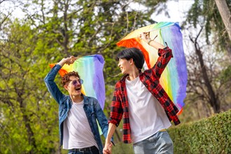 Happy multi-ethnic gay young men raising lgbt flags in a park