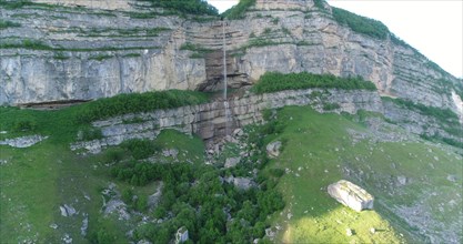 Aerial view of a cliff in the mountains with a waterfall