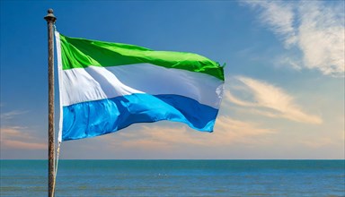 The flag of Sierra Leone, fluttering in the wind, isolated, against the blue sky