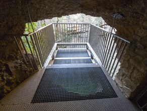 Metal lookout leads through a stone passageway in a cave structure, El Pozo de los Aines, Grisel,