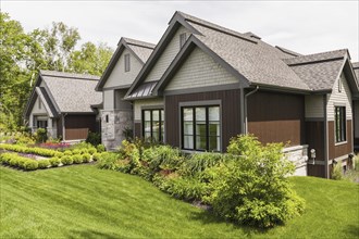Contemporary natural stone and brown stained wood and cedar shingles clad luxurious bungalow style