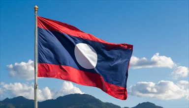 The flag of Laos flutters in the wind, isolated against a blue sky