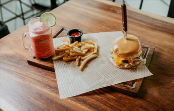 Top view of Hamburger with fries and strawberry mocktail served on a wooden table. Hamburger with