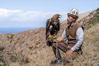 Traditional Kyrgyz eagle hunter with eagle in the mountains, hunting, near Bokonbayevo, Issyk Kul