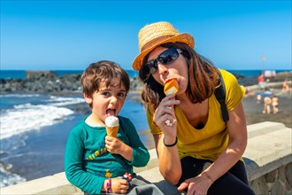 Mother with her little boy son enjoying summer vacation eating ice cream