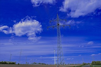 Power pylons with high-voltage lines and wind turbines at the Avacon substation in Helmstedt,