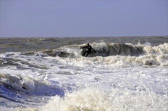 Sylt, North Frisian Island, Schleswig-Holstein, A surfer on a wave in the sea, surrounded by foam,
