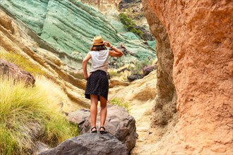 A tourist woman enjoying the natural monument at the Azulejos de Veneguera or Rainbow Rocks in