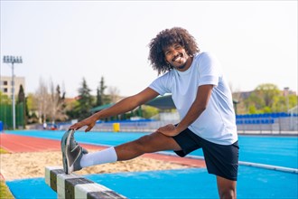 Sportive man with afro hairstyle warming up in an outdoor running track