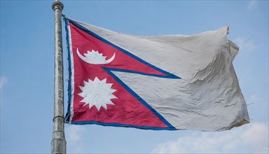 The flag of Nepal, fluttering in the wind, isolated against a blue sky