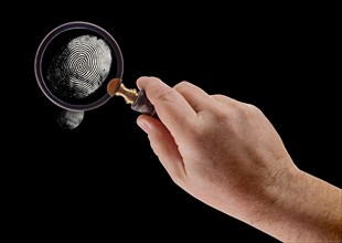 Male hand holding magnifying glass viewing A fingerprint on a black background