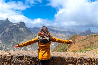 A tourist woman looking at Roque Nublo from a viewpoint with her arms open. Gran Canaria, Spain,