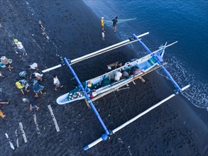 Fishermen unload their catch from their outrigger boat in the morning. Amed, Karangasem, Bali,