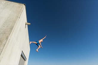 Man jumping from concrete construction, Tjuvholmen, Aker Brygge, Oslo, Norway, Europe