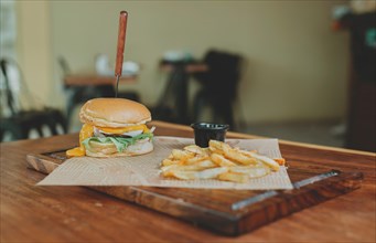 Cheeseburger with french fries served on wooden table with copy space. Delicious hamburger with