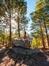 A woman sitting on a stone while hiking to Roque Nublo in Gran Canaria, Canary Islands