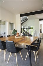 American walnut wood dining table and black leather sitting chairs with ash wood legs in dining