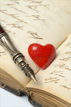 Pen with pen holder and red heart on diary