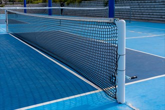 Empty space of a pickleball net in a blue outdoor court wit no people