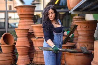 A woman examines a terracotta pot in a pottery workshop