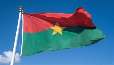 The flag of Burkina Faso flutters in the wind, isolated against the blue sky