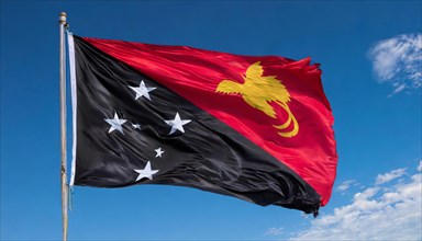 The flag of Papua New Guinea, fluttering in the wind, isolated, against the blue sky