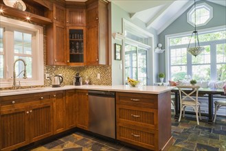 Kitchen with cherry wood cabinets, earth tone slate flooring and breakfast table with sitting bench
