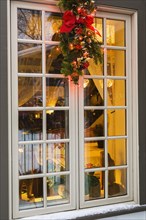 Brown and beige window with illuminated Christmas lights and decorations on an old circa 1886 white