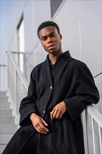 Vertical portrait of an african model posing with black clothes railing on stairs