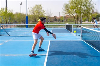 Man in sportive clothes playing pickleball with friends outdoors