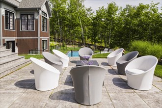 White and grey cloth covered sitting chairs on backyard patio and rear view of contemporary natural