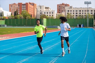 Full length photo of two smiling young african runners training together in an outdoors athletics