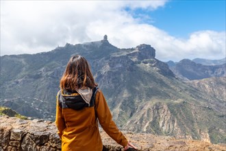 A tourist woman looking at Roque Nublo from a viewpoint on the mountain. Gran Canaria, Spain,