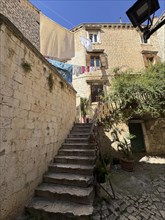 Stone staircase in a sunny alleyway of the old town centre with hanging laundry, Trogir, Dalmatia,