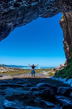 Man hiker in the Algorri cove sea cave on the flysch coast of Zumaia, Gipuzkoa. vertical photo