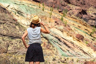 A tourist woman at the Natural Monument Azulejos de Veneguera or Rainbow Rocks in Mogan, Gran