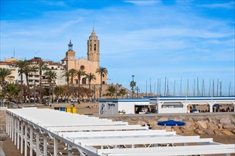 Beach, promenade with view of the church of St Bartholomew and St Thekla in Sitges, Spain, Europe