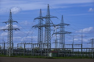 Power pylons with high-voltage lines and wind turbine at the Avacon substation in Helmstedt,
