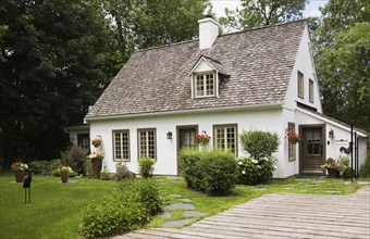 Old circa 1886 white with beige and brown trim Canadiana cottage style home facade with wood plank