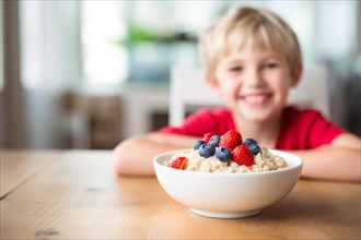 Bowl with oatmeal porridge and berry fruits an dhappy child at breakfast kitchen table. KI