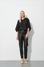 Beautiful elegant blonde woman in black blouse and leather trousers