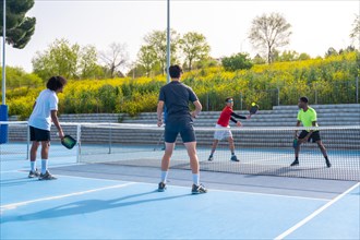 Friends playing pickleball in an outdoor court in a sunny day