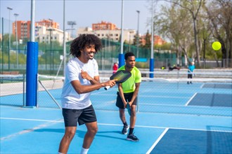 Two african american young sportive male friends enjoying playing pickleball together in an outdoor