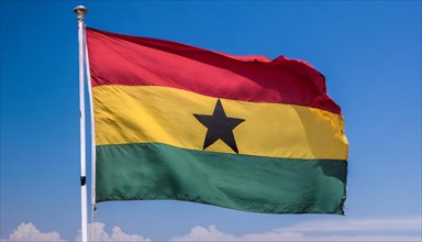 The flag of Ghana flutters in the wind, isolated against a blue sky
