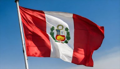 The flag of Peru flutters in the wind, isolated against a blue sky