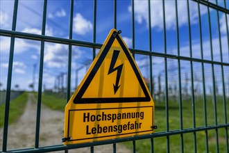 Yellow warning sign with the inscription Hochspannung Lebensgefahr! on a fence of the Avacon